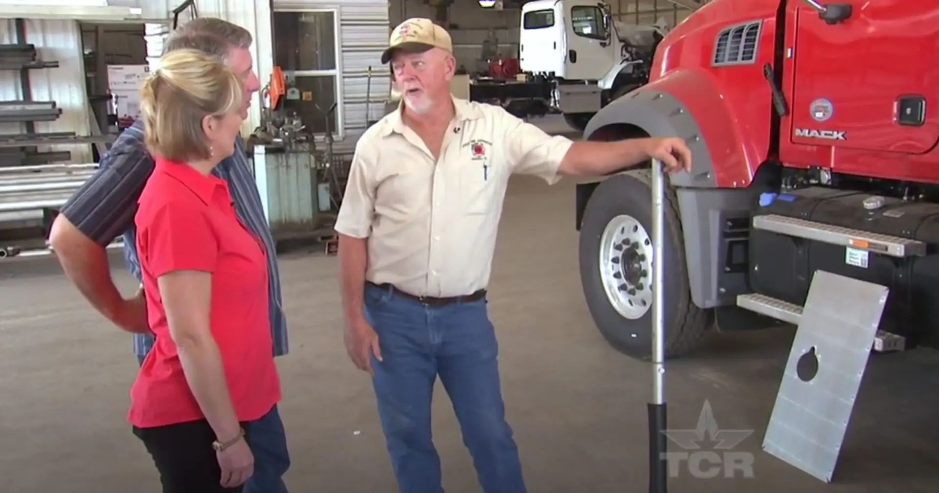 Three people stand near a red truck.