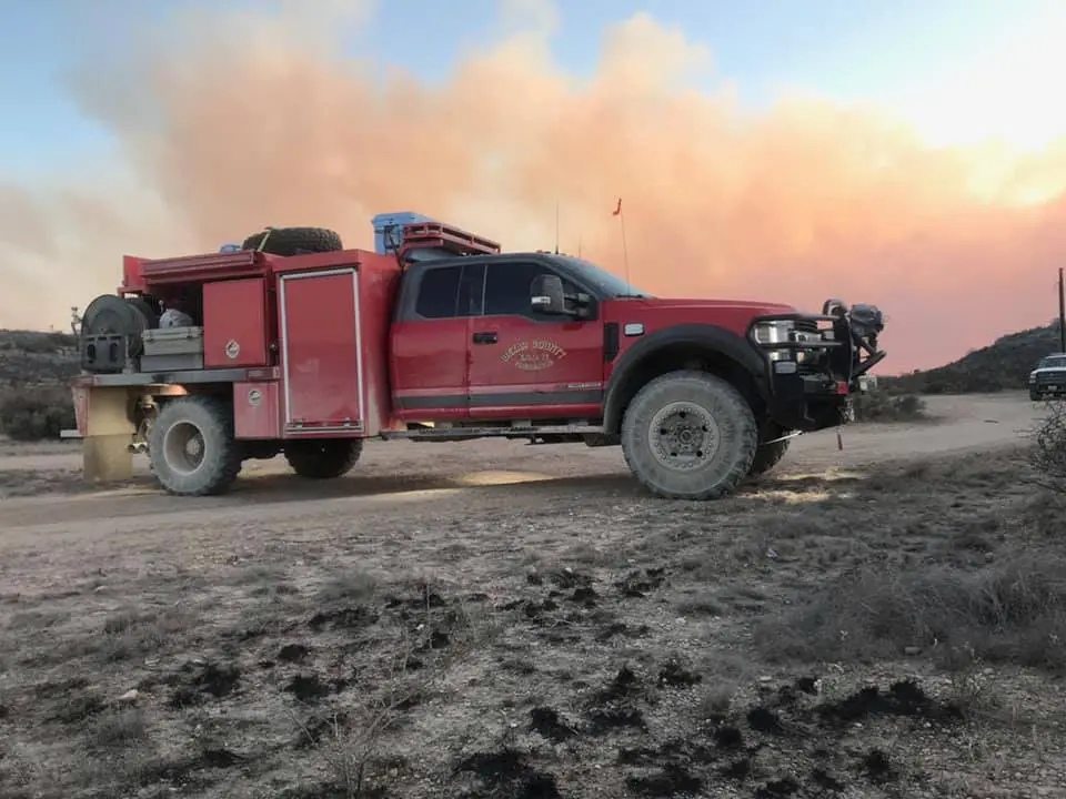 Red fire truck parked on dirt road.